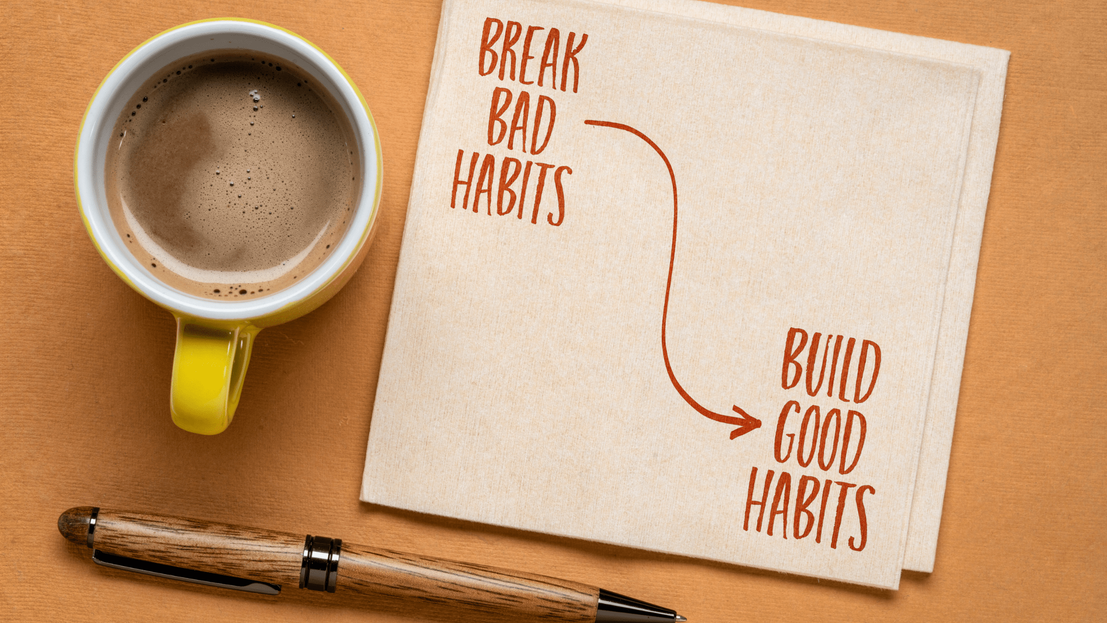 coffee cup and someone writing down habits on a diary.